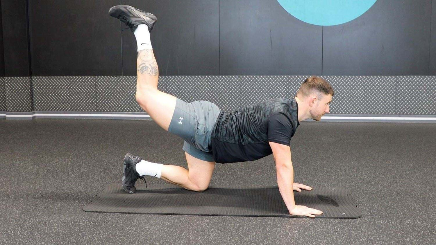 Personal Trainer demonstrating how to do a donkey kick, a glute focused exercise