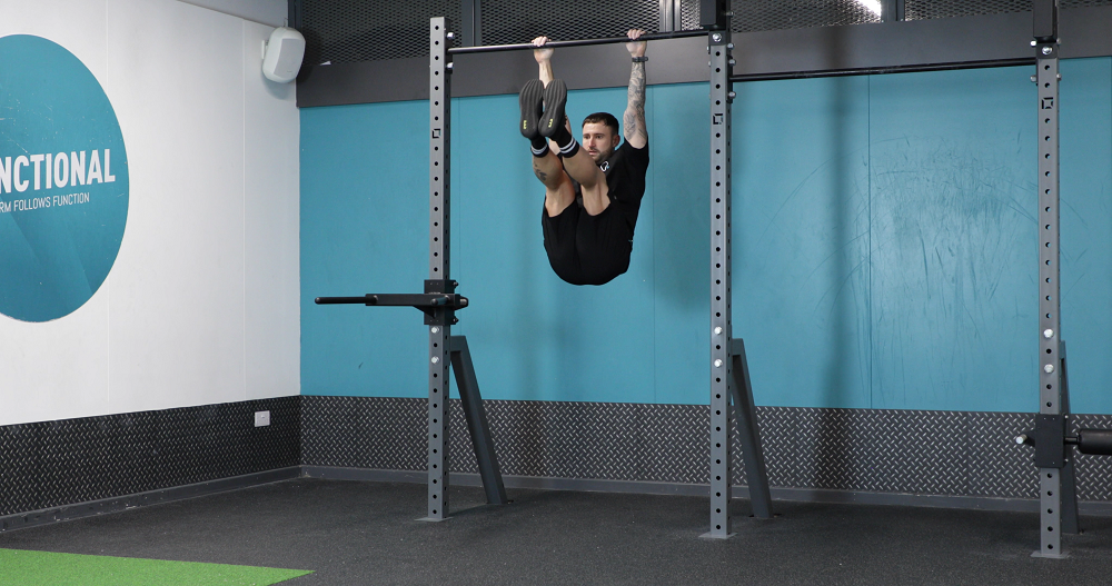 PT demonstrating how to do hanging leg raises exercise