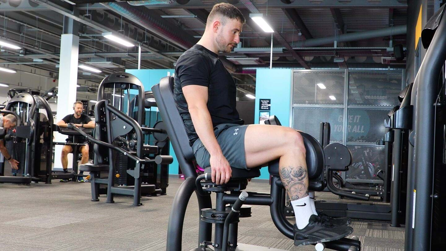 Male PT doing seated hip adduction exercise