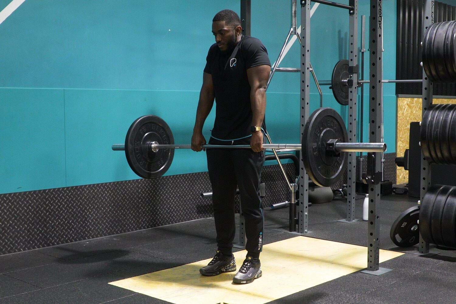 PT doing barbell shrugs