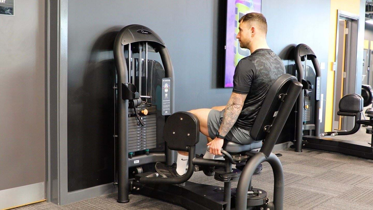 Male PT doing seated hip abduction exercise