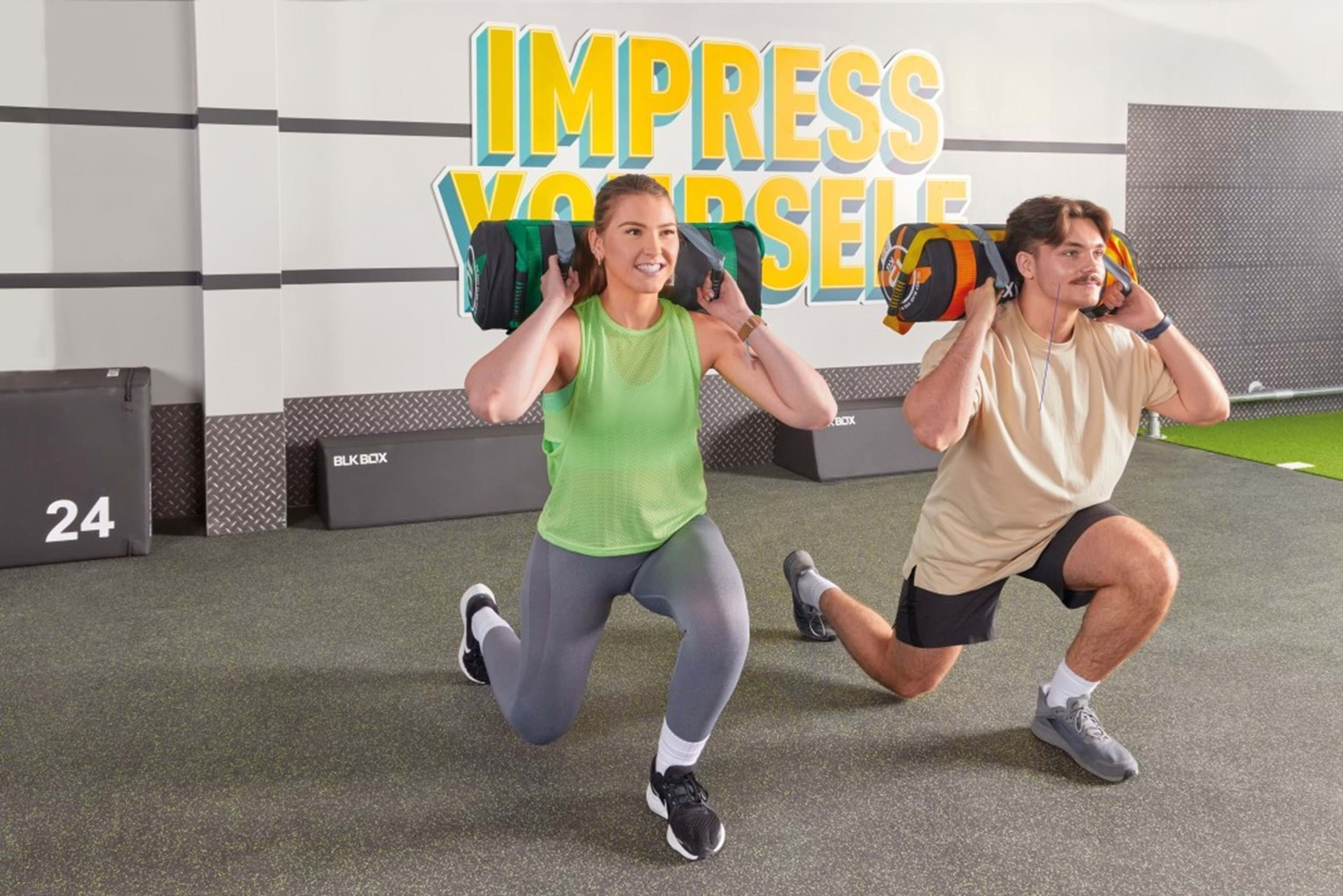 Two people performing sandbag lunges